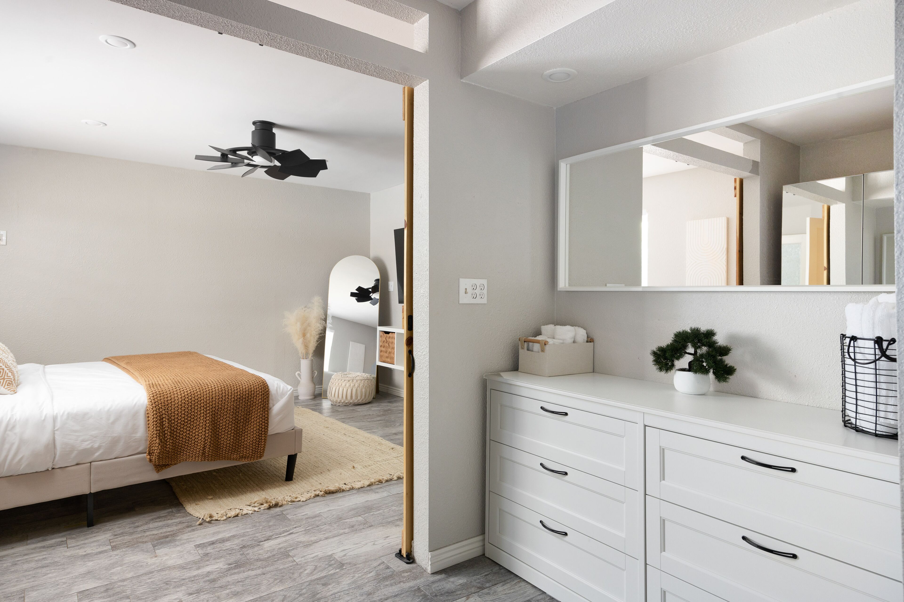 A modern bedroom with a bed, bedside table, and a large mirror.
