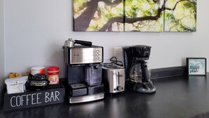 Ein Kaffee-Bereich mit einem Mr. Coffee Café-Barista, einem Toaster von Black & Decker, einer Kaffeemaschine sowie verschiedenen Kapseln und Behältern für Kaffee.