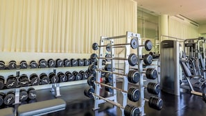 Ein Fitnessstudio mit Krafttrainingsgeräten, darunter ein Squat-Gestell und Kurzhanteln.
