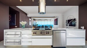 A modern kitchen with a central island, stainless steel appliances, and a view of the ocean.
