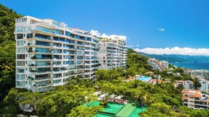 A multi-story hotel with balconies, a pool area, and a view of the ocean.