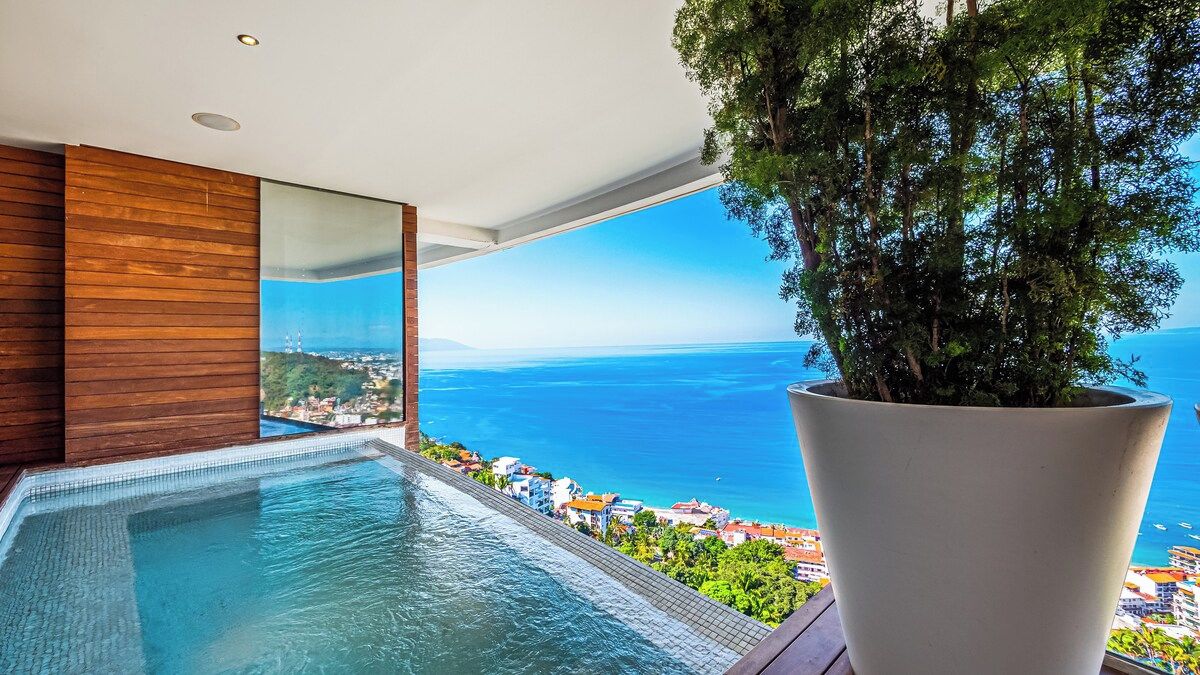 A modern infinity pool with a clear view of the sea and a cityscape.