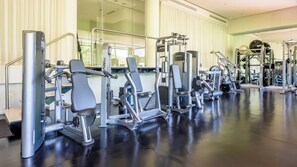 Una palestra con diverse macchine per esercizi, un grande specchio e un pavimento lucido.