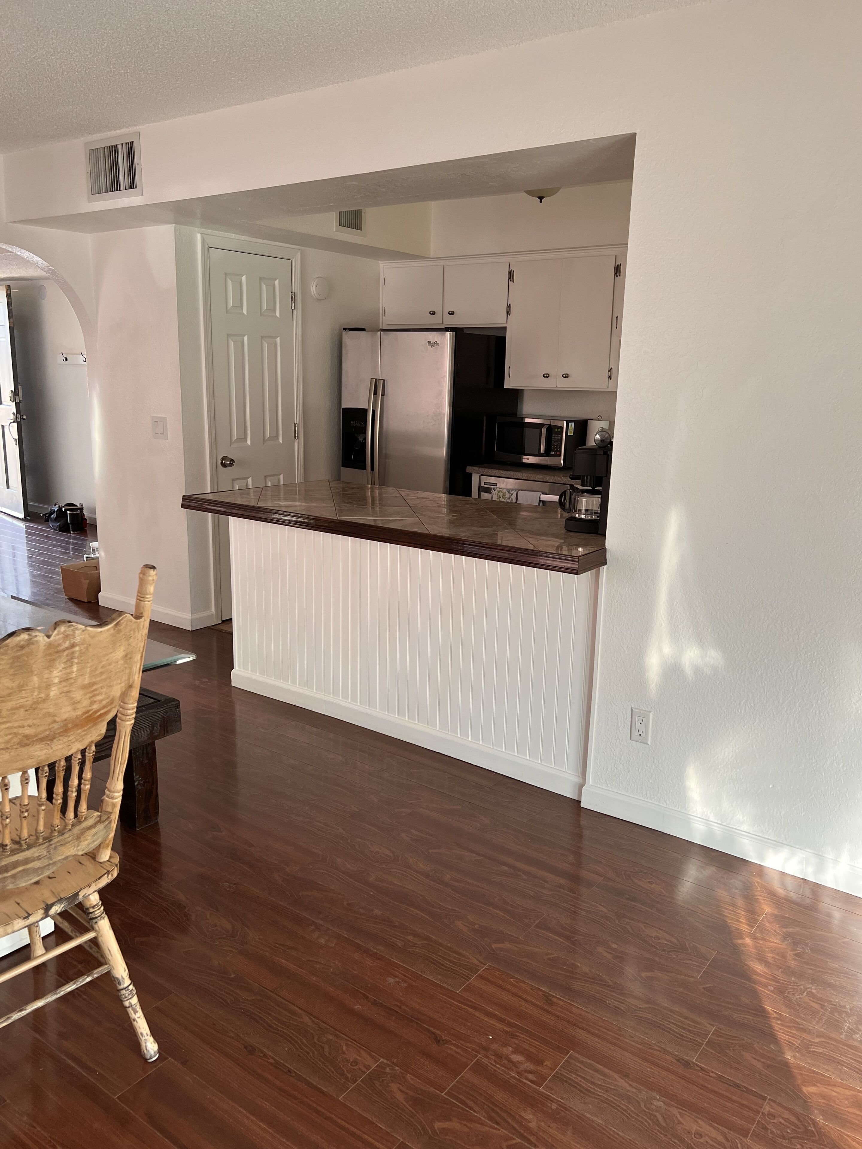Una cocina con armarios blancos, un refrigerador de acero inoxidable y un microondas.