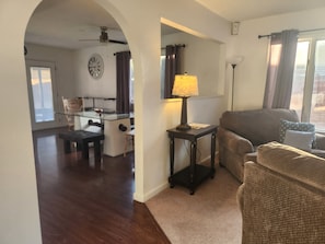 Una sala de estar con sofá, lámpara, una mesa de centro y una zona de comedor con mesa de vidrio y sillas.