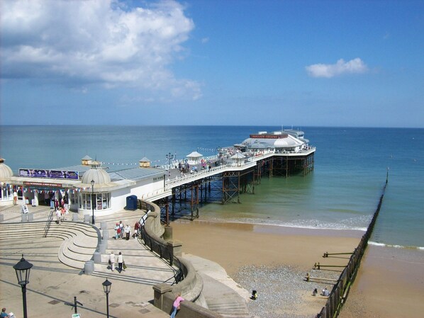 A pier extending into the sea with a pavilion theatre and a promenade area.