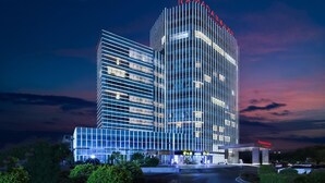 Un hotel moderno con un diseño vertical llamativo, varios pisos y una fachada bien iluminada.