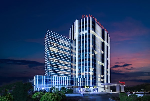 Un hotel moderno con un diseño vertical llamativo, varios pisos y una fachada bien iluminada.