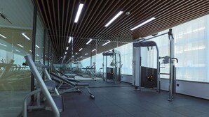 Un gimnasio con equipo de ejercicio, ventanas amplias y un diseño de techo moderno.