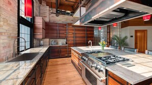 Une cuisine moderne dotée d’un grand îlot central, d’appareils électroménagers en acier inoxydable et de meubles de rangement en bois.