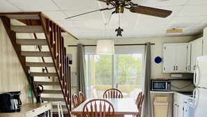 A spacious kitchen with a dining area, a staircase, and a ceiling fan.