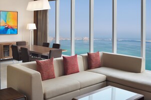 Habitación de hotel moderna con un ventanal que ofrece vistas al mar y al paisaje urbano.