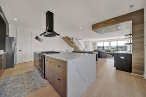 A modern kitchen with a central island, built-in oven, and a stainless steel range hood.