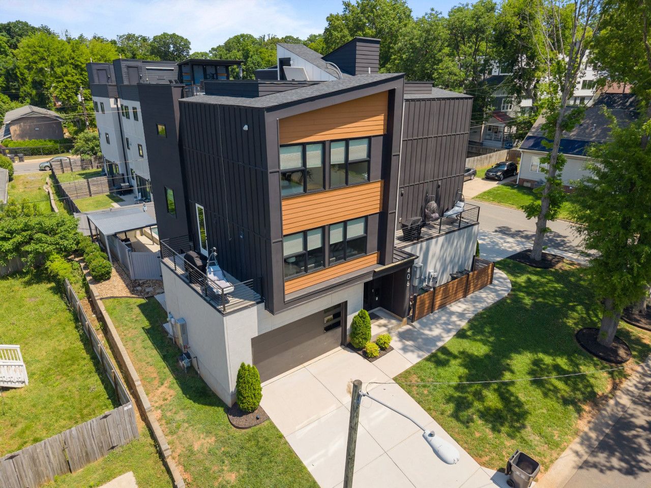 A modern two-story house with a flat roof, large windows, and a small front yard.