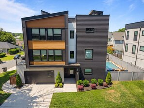 A modern two-story house with a garage, a swimming pool, and a well-maintained lawn.