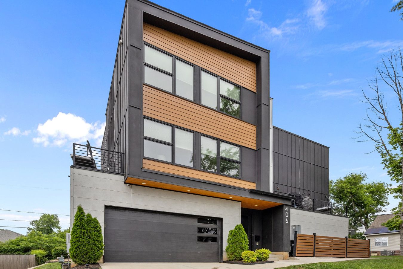 A modern two-story house with a large garage, a balcony, and a well-maintained lawn.