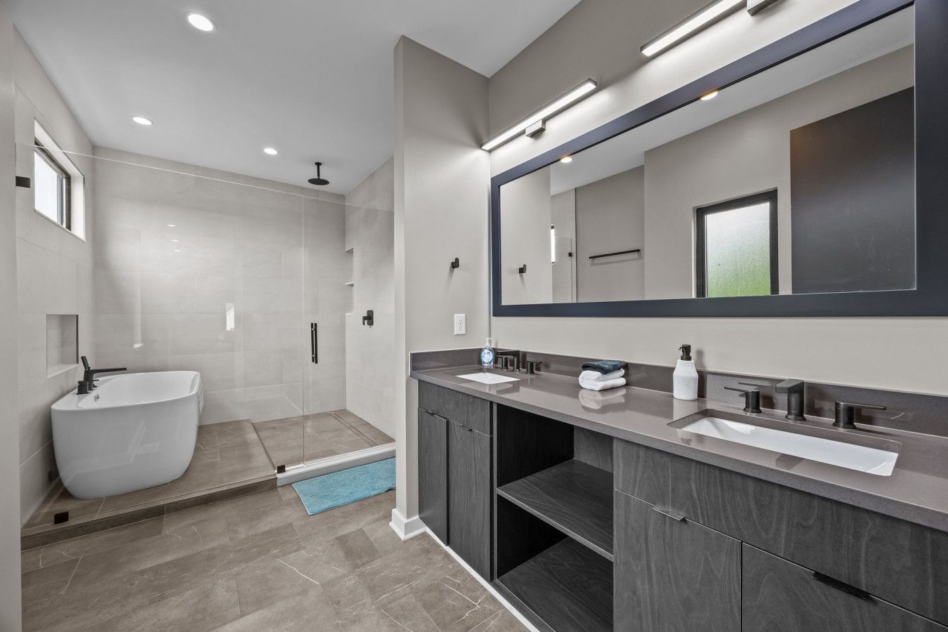 A modern bathroom with a freestanding bathtub, a walk-in shower, and a vanity with a large mirror.