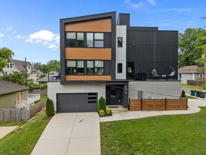 Et moderne hus med to etager, garage, overdækket terrasse og velholdt græsplæne.