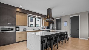Una cocina moderna con una isla grande, armarios de madera oscura y una campana extractora de acero inoxidable.