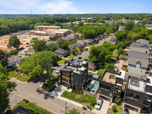 A residential area with modern houses, a swimming pool, and a large industrial building in the background.