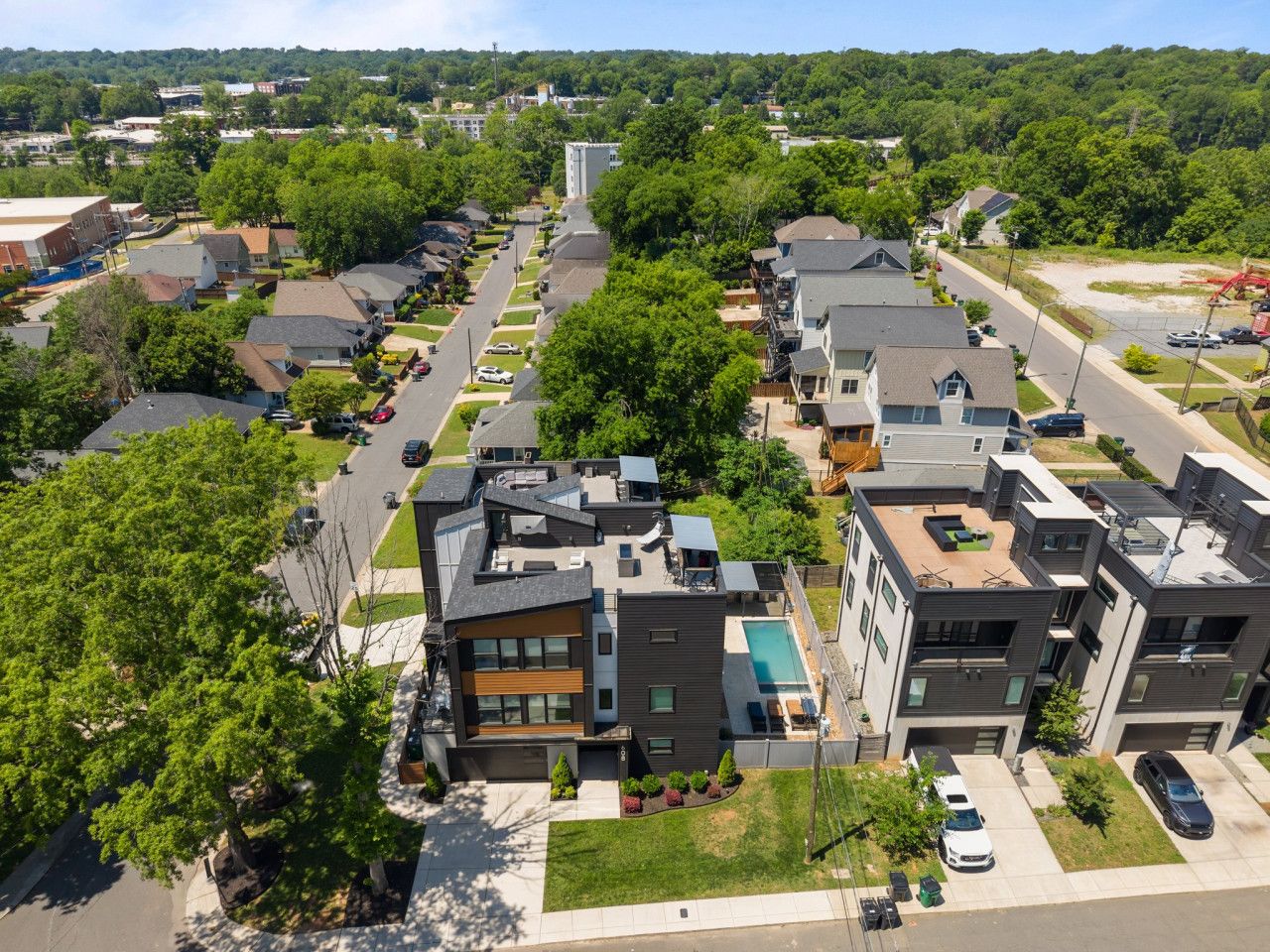 A modern residential area with detached houses, a swimming pool, and a clear sky.
