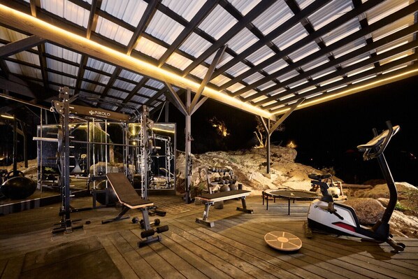 A gym with various exercise equipment, a bench, and a rowing machine.