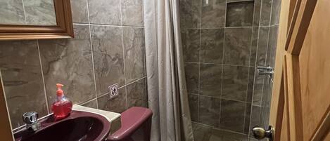 A bathroom with a marble sink, a toilet, and a shower.