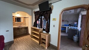A compact kitchen with a built-in oven, a sink, and a stove. There is a wooden bench and a small table with a TV mounted above it. - Hotel Posada don Miguel (Panajachel)