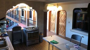 A kitchen with a gas stove, oven, and a dining table with chairs. There is a staircase leading to an upper level. - Hotel Posada don Miguel (Panajachel)