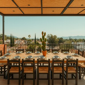 A dining area with a table set for six, overlooking a cityscape with mountains in the distance. - Casa Acueducto (Oaxaca)