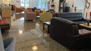 A spacious lobby with a reception desk, seating area with sofas and chairs, a coffee machine, and a refrigerator. - July Apartments (Philipsburg)