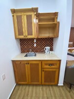 Una cocina compacta con armarios de madera, un lavamanos y una encimera.