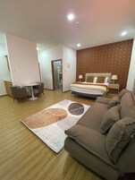 Habitación de hotel con una cama, un sofá, un escritorio y una silla. Pared con diseño y suelo de madera.