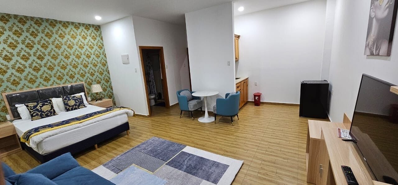 A modern hotel room with a bed, a desk, a chair, and a small table.