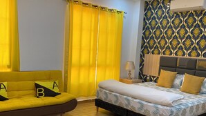 A hotel room with a bed, a sofa, a rug, and a patterned wall. - July Apartments (Philipsburg)