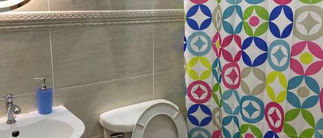 Un bagno con il water, lavandino e tenda da doccia.