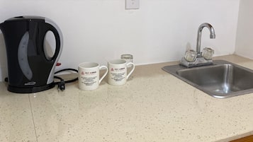 Cuina amb cafetera, dues tasses, un rentaplat i armaris de fusta.
