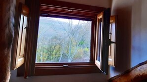 A room with a large window, wooden beams, and a view of trees and hills. - Charming accommodation, next to Ribera del Duero and Hoces del Duratón (aldeasoña)