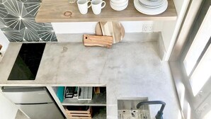 A compact kitchen with a built-in refrigerator, a sink with a faucet, and a countertop with various kitchen items. - Loreto80- NEW Studio Pitaya, in downtown by beach (Loreto)