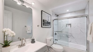Ein modernes Badezimmer mit großem Spiegel, Waschbecken, Toilette und einer Duschkabine.