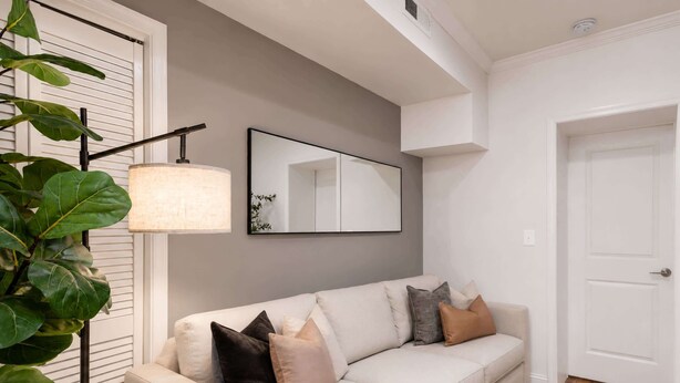 Una sala de estar moderna con un sofá blanco, un espejo grande y una lámpara de pie.