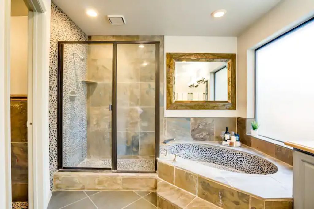 Une salle de bain moderne avec une douche à parois de verre, une baignoire sur pieds et un grand miroir.