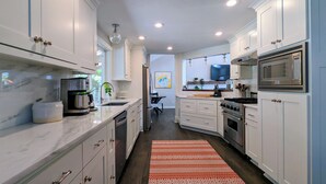 A modern kitchen with white cabinets, stainless steel appliances, and a patterned rug. - Arioso House - Style Inspired by Classical Music! (Newberg)