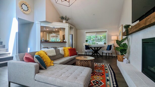 A spacious living room with a gray sofa, a round coffee table, and a fireplace. - Arioso House - Style Inspired by Classical Music! (Newberg)