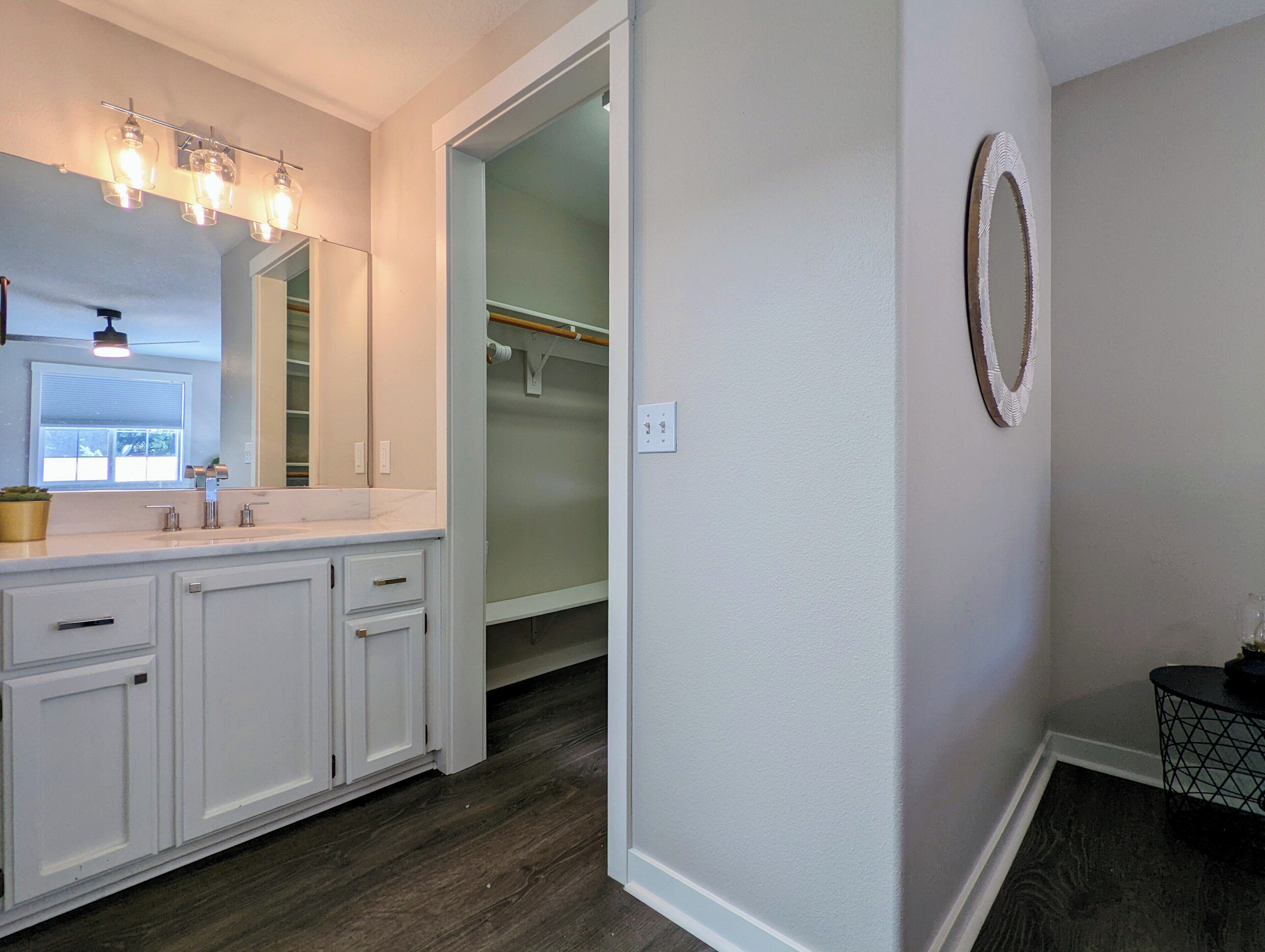 Une salle de bain avec un meuble-lavabo blanc, un miroir et un luminaire placé au-dessus du miroir.