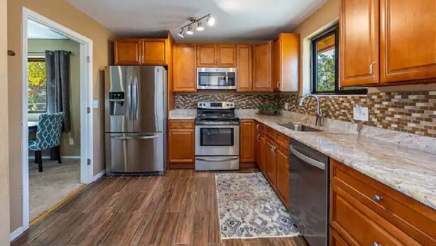 A modern kitchen with wooden cabinets, stainless steel appliances, and a tiled backsplash.