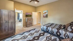 A bedroom with a bed, a wardrobe, a ceiling fan, and a door leading to another room.