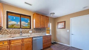 A kitchen with wooden cabinets, a dishwasher, and a tiled backsplash.
