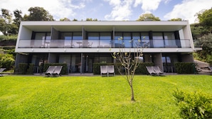 A modern two-story building with a flat roof, large windows, and a well-maintained lawn with sun loungers. - Studio Lower-level w/ kitchenett and patio (Santana)