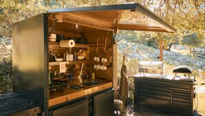 A compact outdoor kitchen with a sink, stove, and storage cabinets, surrounded by trees and a grill. - Paradise Ranch Inn - Mindful Tent (Three Rivers)